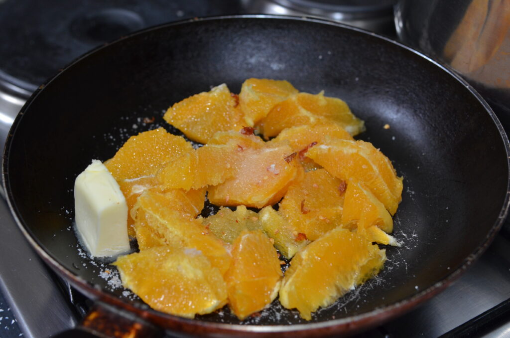 finely chopped oranges in a pan with butter
мелко нарезанные апельсины на сковороде со сливочным маслом
